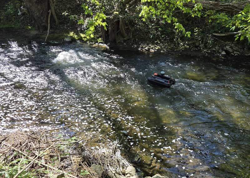 Fluss mit Stömung. Ein Echolotboot fährt stromaufwärts